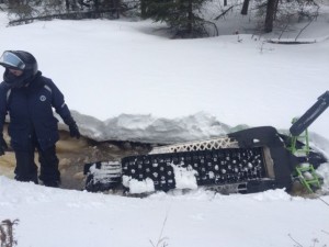 Snowmobile upside down in the bottom of a creek